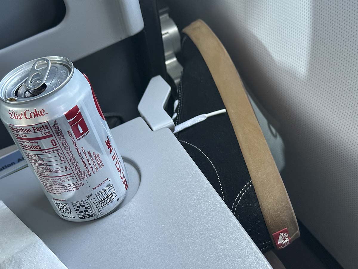 Crossing my legs in Frontier Airlines A321 UpFront Plus with the tray table down